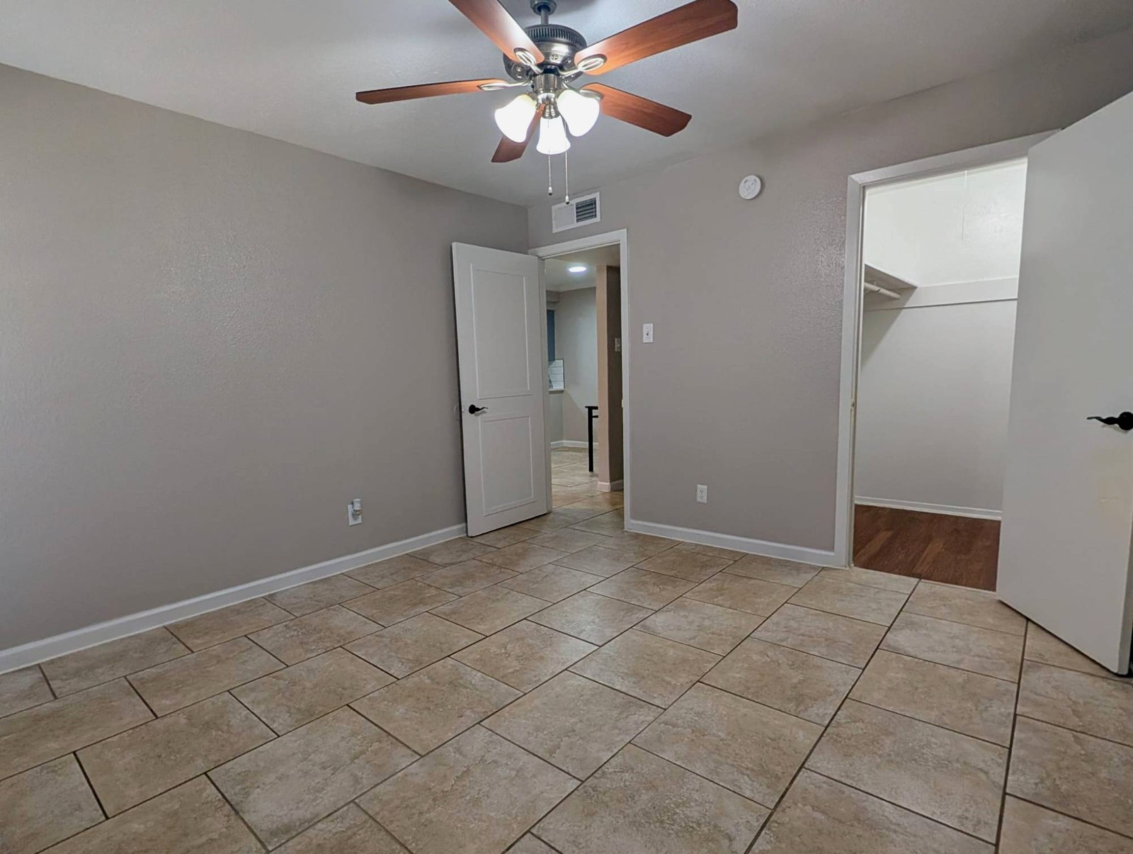 Bedroom with tile flooring, ceiling fan and walk-in closet